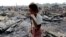 A woman walks among debris after fire destroyed shelters at a camp for internally displaced Rohingya Muslims in the western Rakhine State near Sittwe, Myanmar. 