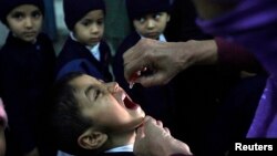 FILE - A female polio worker gives polio vaccine drops to a child in Lahore.