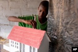 FILE—Mouhamed Sall, who is deaf, and known for his talent for drawing and manual activities, paints a small house he built in Pikine, Senegal, March 18, 2024.