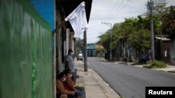 FILE - Residents wait outside a house and near a white flag as a sign to ask for food, in a low-income neighborhood during the coronavirus outbreak, in San Salvador, El Salvador, May 14, 2020.