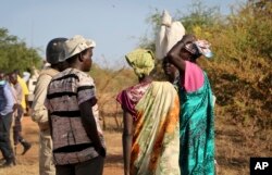 FILE - Women speak to members of a UN peacekeeping patrol as they walk to get food in Bentiu, a 38 kilometers (24 mile) journey where there are fears of being attacked on the main road, from Nhialdu in South Sudan, Dec. 7, 2018.