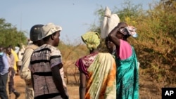 In this photo taken Dec. 7, 2018, women speak to members of a UN peacekeeping patrol as they walk to get food in Bentiu, a 38 kilometers (24 mile) journey where there are fears of being attacked on the main road, from Nhialdu in South Sudan. 