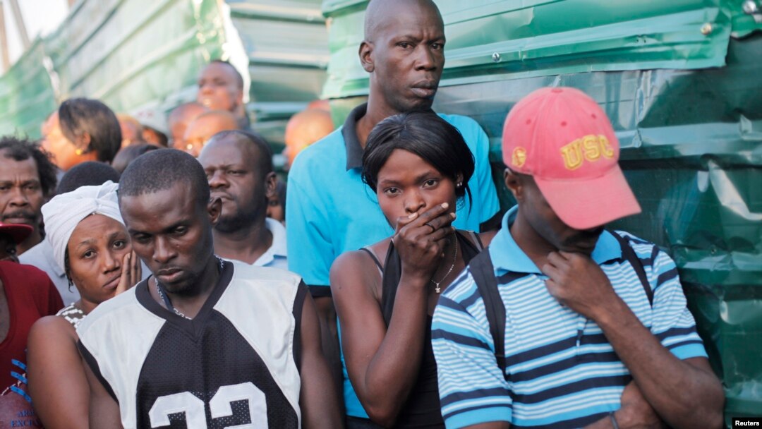People stand outside the morgue where the dead bodies of people killed when a carnival float hit power lines were taken in Port-au-Prince, Feb. 17, 2015.