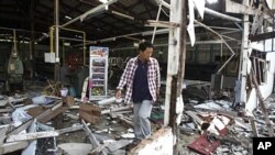 A man walks through rubles at the destroyed silk factory following the clash between Thailand and Cambodia in Surin province, northeastern Thailand, April 27, 2011.