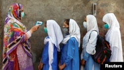 Students wear protective face masks as they have their temperature checked before entering a class, after the government allowed the reopening of schools from grade six to eight amid the coronavirus pandemic, in Peshawar, Pakistan.