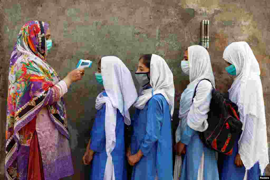 Students wear protective face coverings as they have their temperature checked before entering a class, after the government permitted the reopening of schools from grade six to eight during the coronavirus pandemic, in Peshawar, Pakistan.