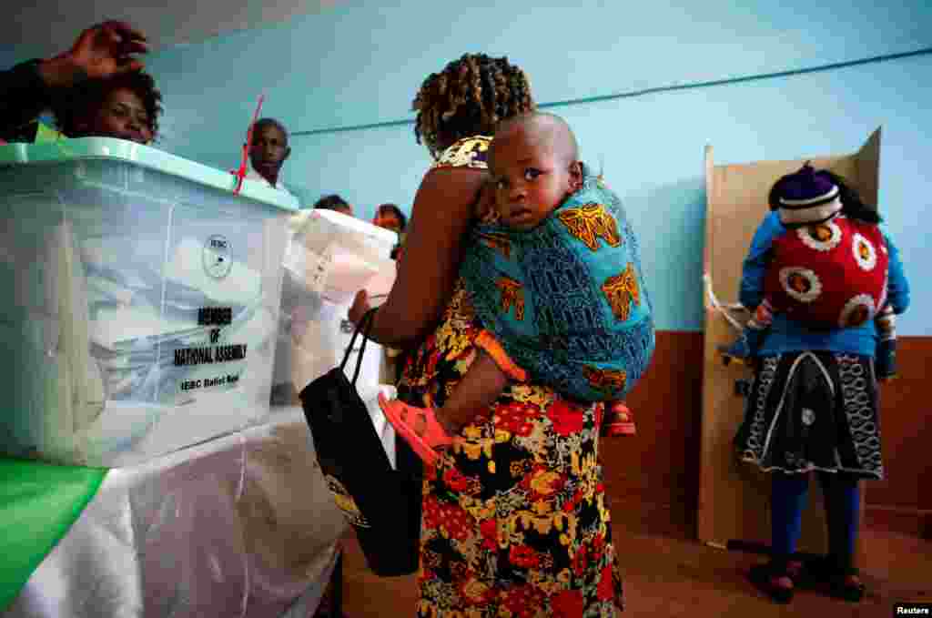 Women carrying babies cast their vote in Gatundu in Kiambu county, Kenya, Aug. 8, 2017. 