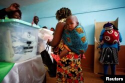 Women carrying babies cast their vote in Gatundu in Kiambu county, Kenya, Aug. 8, 2017.