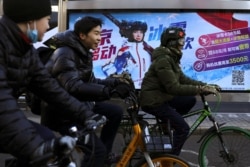 People ride bicycles past a China Mobile advertisement with an image of freestyle skier Eileen Gu, at a bus stop in Beijing, China, January 11, 2022. (REUTERS/Tingshu Wang)