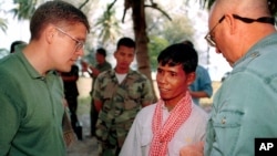 Former Khmer Rouge guerilla Mao Run, center, speaks to Robert L. Jones, left, deputy assistant of Defense for POW/MIA on the island of Koh Tang, Cambodia, Jan 28, 2000. Mao Run was part of the Khmer Rouge unit who fought with U.S. Marines on May 15, 1975. (AP Photo/Heng Sinith)