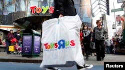 FILE - Shoppers pass by the Toys R Us store at Times Square in New York.