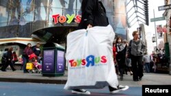 Warga membawa kantong plastik belanja dari toko Toys R Us di Times Square, New York City.