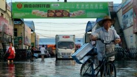 FILE - In this Monday, July 26, 2021 file photo, a man carries goods on his bicycle as he walks out of the the Yubei Agricultural and Aquatic Products World in Xinxiang in central China's Henan Province.
