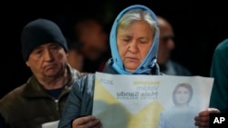 A woman looks at a paper promoting Moldova's President Maia Sandu in Magdacesti, Moldova, Oct. 17, 2024, ahead of a presidential election and a referendum on whether to enshrine in Moldova's Constitution its path to European Union membership.