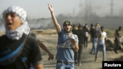 A Palestinian protester reacts to tear gas fired by Israeli troops during clashes near the border with Israel, in the east of Gaza City, Oct. 16, 2015. 