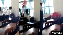 Nhóm nữ sinh dùng ghế nhựa phang liên tiếp vào đầu, đấm túi bụi, kéo và giật tóc một nữ sinh cùng lớp (ngồi) trong khi các em khác đứng xem. (Ảnh từ clip trên YouTube).
