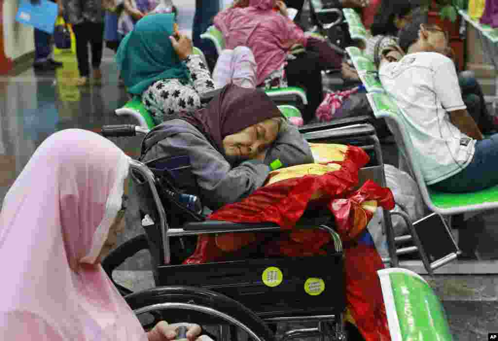 A patient takes a nap in her wheelchair as she waits with others at the registration desk at Dharmais Cancer Hospital in Jakarta, Indonesia. The hospital&#39;s information system was affected by the weekend&#39;s worldwide cyber attack.