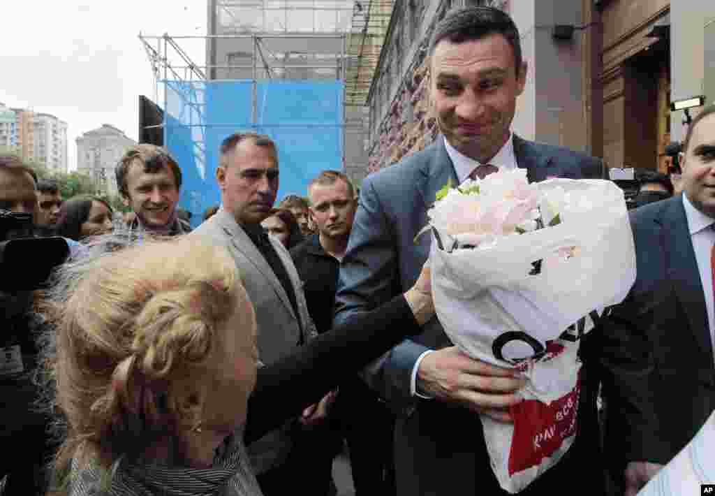 An elderly woman gives flowers to Kyiv mayor Vitaly Klitschko, chairman of the Ukrainian party Udar (Punch) during a rally near the city council in Kyiv, June 5, 2014.