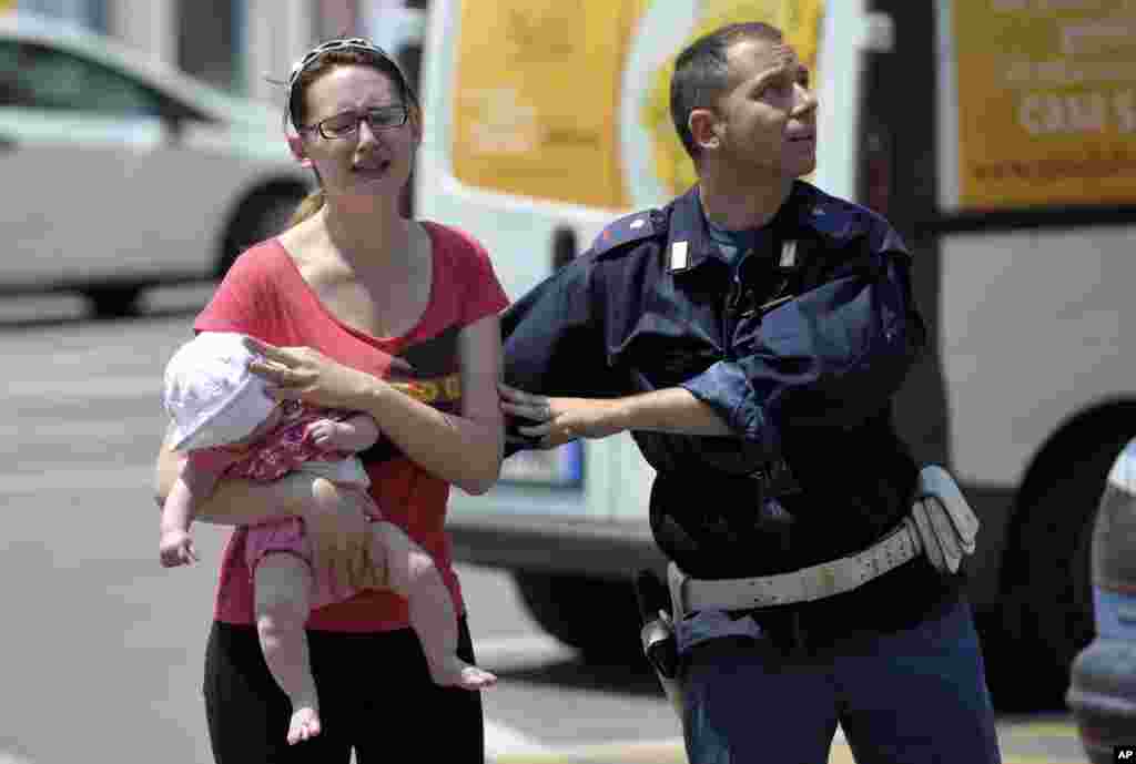 Un polic&iacute;a italiano ayuda a una mujer que carga a su beb&eacute; durante el temblor y las r&eacute;plicas que afectaron severamente la ciudad de Mirandola.