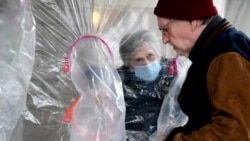 Lynda Hartman is a 75 wife, visiting her 77-year-old husband, Len Hartman. They are using "hug tent" set up outside the Juniper Village assisted living center in Louisville, Colorado, on Wednesday, Feb. 3, 2021. (AP Photo/Thomas Peipert)