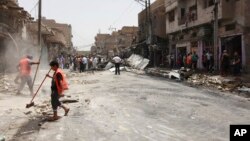 Para pekerja tengah membersihkan lokasi ledakan bom mobil di kawasan Allawi, Baghdad (14/7). 