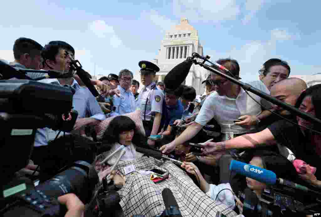 Wheelchair-bound Japanese lawmaker Eiko Kimura (C) is surrounded by the media upon her arrival at Parliament in Tokyo. Two lawmakers with serious paralysis took their seats in Japan&#39;s upper house, marking the first time people with severe disabilities have served in the body.