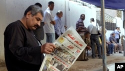 Čovek ispred birališta čita lokalne novine na čijoj naslovnoj strani piše "Egipat iznenadio svet",Kairo, 27. maj 2014.