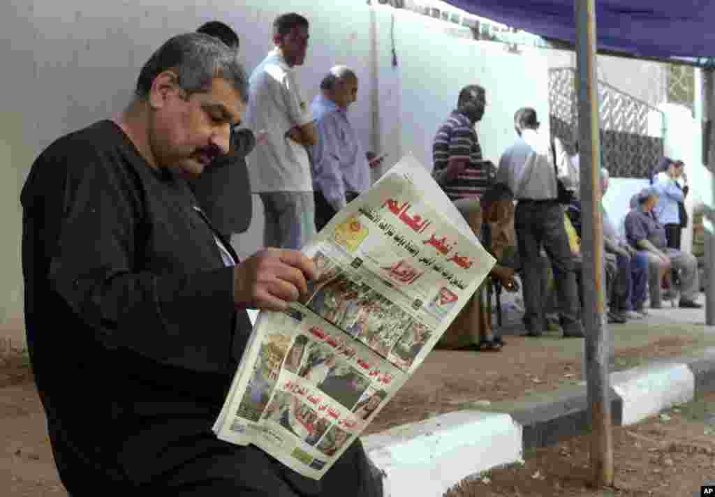 A man reads a local newspaper with the headline in Arabic reading, "Egypt surprises the world," outside a polling station in Cairo, May 27, 2014.