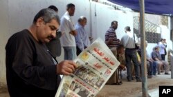 Seorang pria membaca koran dengan judul berita utama "Mesir Kejutkan Dunia", di luar sebuah TPS di Kairo (27/5). (AP/Amr Nabil)