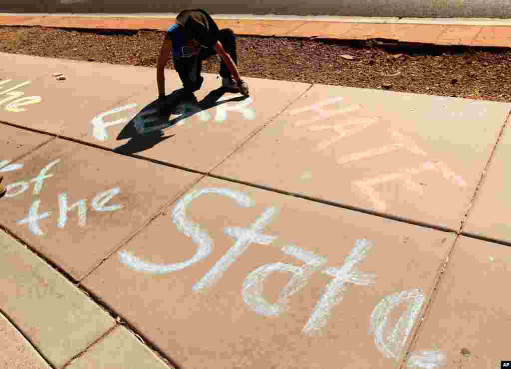 Маргарет Плюс малює крейдою на тротуарі під час демонстрації поблизу відділення Імміграційної та прикордонної служби США у Феніксі.