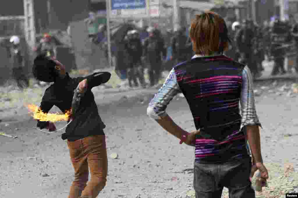 A worker throws a gas bomb after clashes broke out during a protest in Phnom Penh, Jan. 3, 2014. 