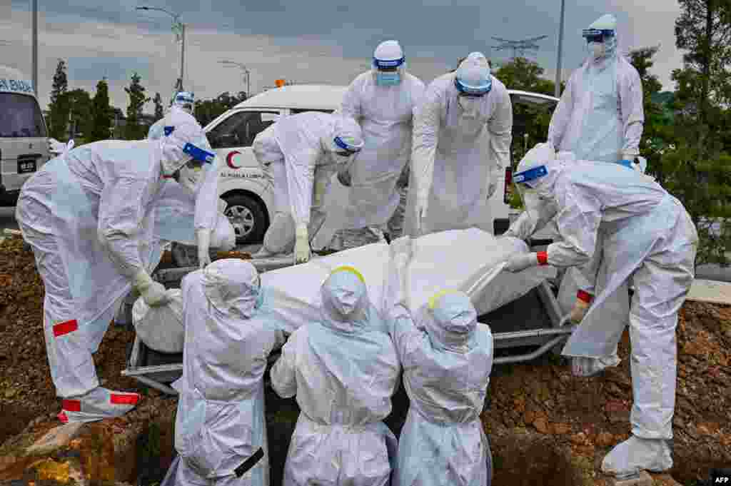 Volunteers wearing protective suits lay down the body of a Covid-19 victim for burial at the Raudhatul Sakinah Muslim cemetery in Kuala Lumpur, Malaysia.
