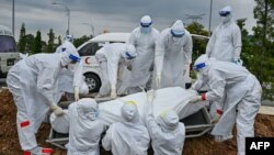 Volunteers wearing protective suits lay down the body of a Covid-19 victim for burial at the Raudhatul Sakinah Muslim cemetery in Kuala Lumpur, Malaysia.