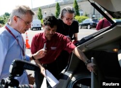 Carnegie Mellon University professor Raj Rajkumar, center, explains the workings of the university's autonomous car in Washington, June 24, 2014. The 2011 Cadillac SRX is able to control steering, speed and braking in harmony with autonomous systems that detect and avoid obstacles in the road.