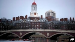FILE - Rowers paddle down the Charles River past the campus of Harvard University in Cambridge, Mass., March 7, 2017. A federal judge in Boston heard closing arguments Friday in a highly publicized lawsuit alleging that elite Harvard discriminates against