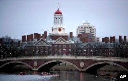 FILE - Rowers paddle down the Charles River past the campus of Harvard University in Cambridge, Mass., March 7, 2017.