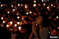 FILE - A woman reacts during a candlelight vigil to mark the 28th anniversary of the crackdown of the pro-democracy movement at Beijing's Tiananmen Square in 1989, at Victoria Park in Hong Kong, China June 4, 2017.