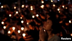 FILE - A woman reacts during a June 4, 2017, candlelight vigil at Victoria Park in Hong Kong to mark the 28th anniversary of the crackdown of the pro-democracy movement at Beijing's Tiananmen Square.