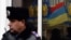 A Ukrainian police officer stands by as the flags of radical party Svoboda (Freedom) are reflected in the window during a protest against political repression in front of the Ukrainian Interior Ministry headquarters in Kiyv, Nov. 28, 2013.