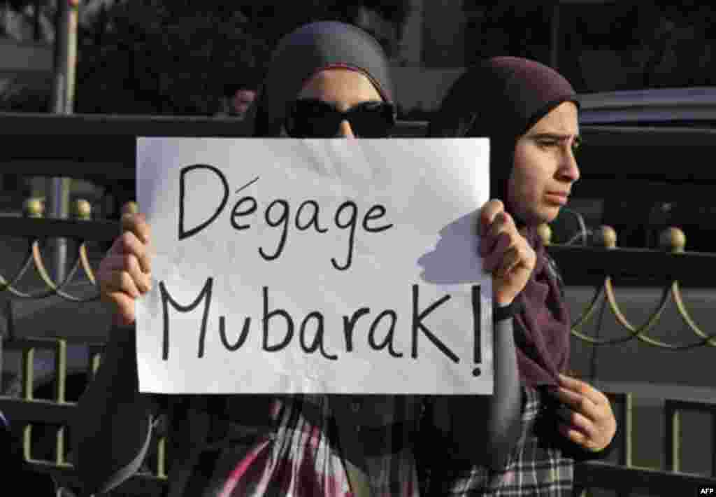 Women carry a poster reading in French "Mubarak get out" during a protest in Cairo, Egypt, Monday Jan. 31, 2011. A coalition of opposition groups called for a million people to take to Cairo's streets Tuesday to ratchet up pressure for President Hosni Mub