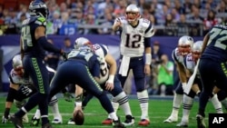 ທ້າວ Tom Brady (12) ຜູ້ແກວ່ງບານ ຫຼື quarterback ທີມ Patriots ແຂ່ງກັບ ທີມSeattle Seahawks ໃນຊ່ວງທຳອິດ ໃນການຊີງ Super Bowl ວັນທີ 1 ກຸມພາ 2015 ທີ່ເມືອງ Glendale ລັດ Arizona.