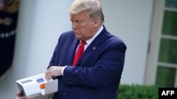 El presidente Donald Trump sostiene un dispositivo para realizar la prueba del nuevo coronavirus en 5 minutos de Abbott Laboratories durante su conferencia de prensa diaria en la Casa Blanca sobre COVID-19 el 30 de marzo de 2020.