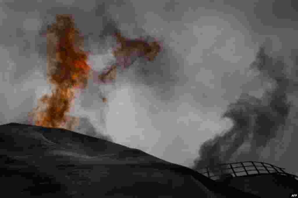 A fuel tank of a power station burns on the frontline of the outskirts of the city of Ajdabiya, south of Benghazi, eastern Libya, Monday, March 21, 2011. The international military intervention in Libya is likely to last "a while," a top French official s