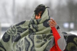 A migrant wraps himself in a blanket while walking through the snow at the Lipa camp northwestern Bosnia, near the border with Croatia, Dec. 26, 2020.