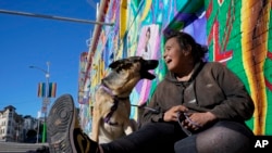 Victoria Solomon igra se sa svojim psom, Gypsy, dok čeka da se njezine stvari osuše u San Franciscu, ponedjeljak, 12. prosinca 2022. (AP Photo/Godofredo A. Vásquez)