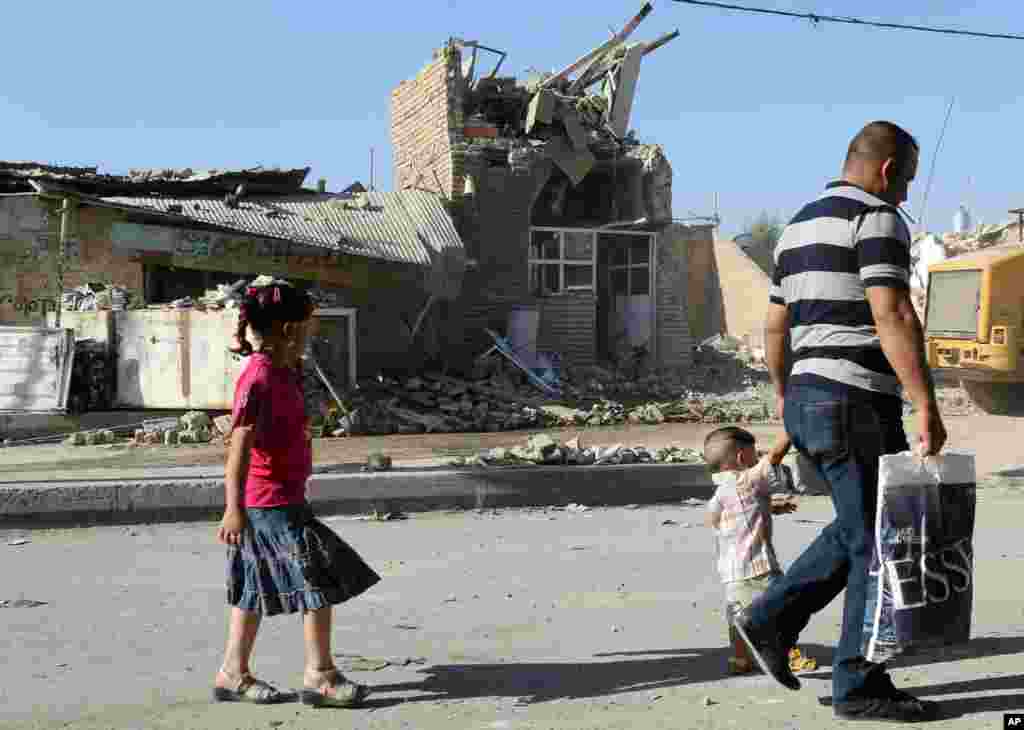 People pass by the ruins of the al-Hussein Shi'ite mosque day after a suicide bomber struck in Musayyib, Iraq, Sept. 30, 2013.
