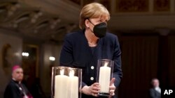 Kanselir Jerman Angela Merkel memegang lilin dalam acara untuk mengenang korban meninggal akibat COVID-19 di Berlin, Jerman Minggu (18/4). 