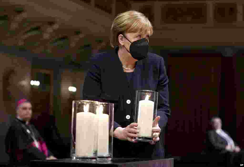 German Chancellor Angela Merkel holds a candle during a memorial service in Berlin, in remembrance of the country&#39;s COVID-19 dead.