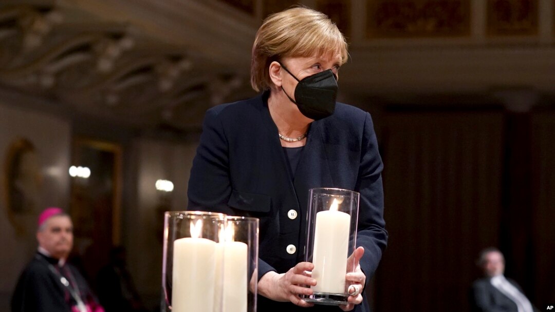 Kanselir Jerman Angela Merkel memegang lilin dalam acara untuk mengenang korban meninggal akibat COVID-19 di Berlin, Jerman Minggu (18/4). 
