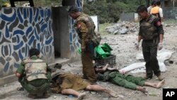 Soldiers stand near two dead bodies at Gote Twin police outpost after an attack in Gote Twin, Naung Cho township, northern Shan State, Myanmar, Aug. 15, 2019. 